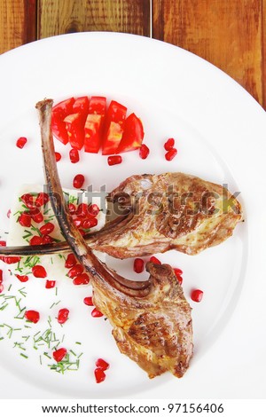 main course: grilled ribs with rice and tomatoes on white dish over wood