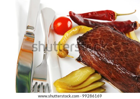 meat and peppers with knife and fork on white