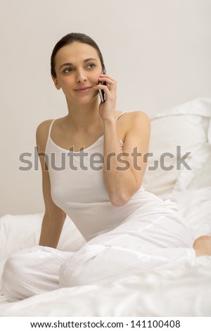 Young girl using black smart phone on bed at home