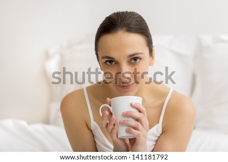 Woman in bed drinking tea. Female enjoying coffee in the bedroom at home