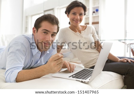 Couple using credit card to shop on line. Laptop.indoor on couch