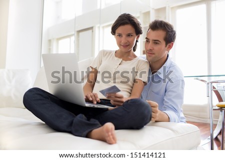 Couple using credit card to shop on line. Laptop.indoor on sofa