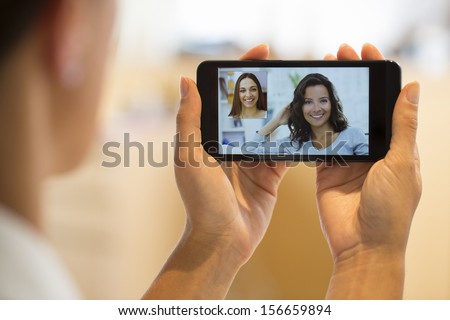 Closeup of a female hand holding a cell phone during a skype video call with her friend