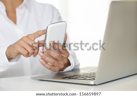 Woman hands with cell phone and computer keyboard, indoor