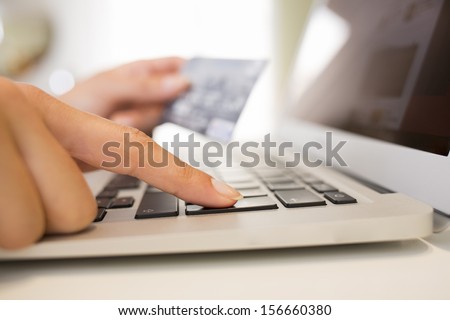 Close-up woman\'s hands holding a credit card and using computer keyboard for online shopping