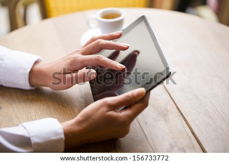 Close up of hands woman using her tablet pc in restaurant cafe Close up of hands woman using her tablet pc in restaurant cafe