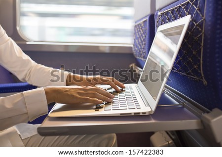 Close-up woman hands typing on a laptop keyboard, in the train