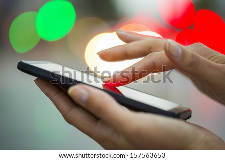 Mobile phone in a woman\'s hand, night, city ??of Light background, sms, message, e-mail