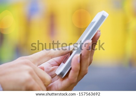 Mobile phone in a woman\'s hand, yellow store background, message, sms, e-mail