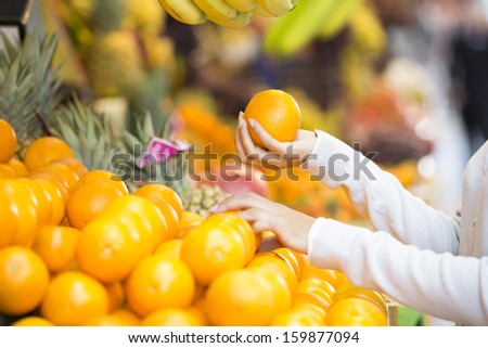 Woman buys fruits and vegetables at a market, banana orange grape