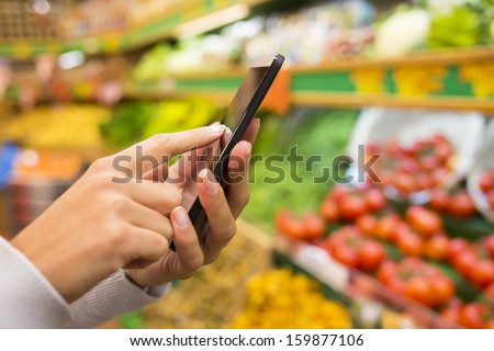 Woman Using Mobile Phone While Shopping In Supermarket, Vegetable Department Store