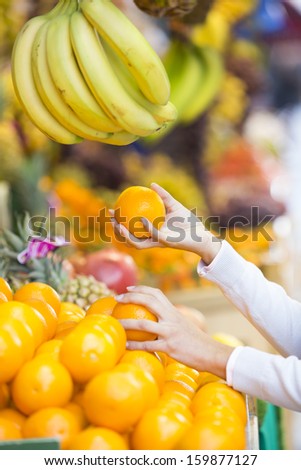 Woman buys fruits and vegetables at a market, banana orange grape