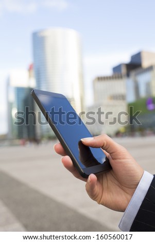 Businesswoman sending messages with her mobile phone in front of building Businesswoman sending messages with her mobile phone in front of building