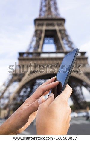 Woman in Paris using her Mobile Phone in front of Eiffel Tower