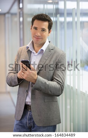 Handsome Business man at the office on phone, sms, e-mail, looking camera