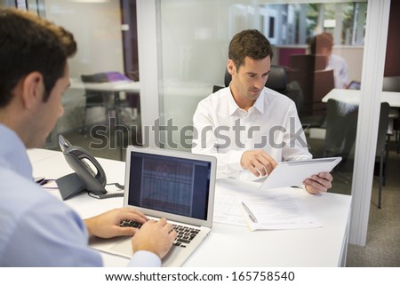 Two businessmen working in office with laptop and tablet pc