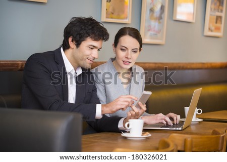 Business-team working on laptop at coffee bar, looking a mobile phone
