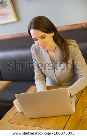 Pretty woman working on laptop in coffee bar, restaurant