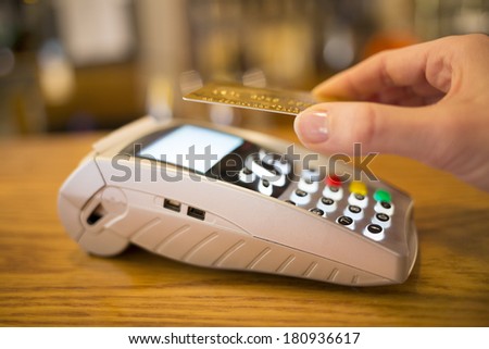 Woman paying with NFC technology on credit card, restaurant, shop
