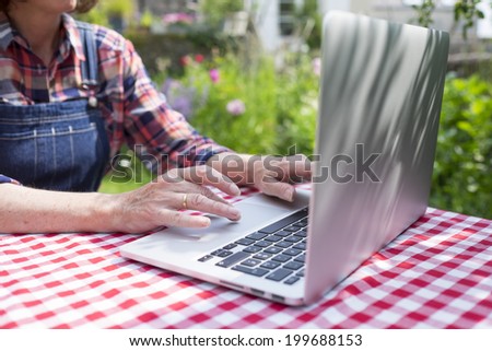 Senior woman using a laptop computer in her garden