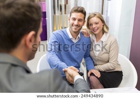Young couple shaking hand real-estate agent in agency office