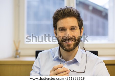 Portrait of handsome hipster style bearded man in office. Looking camera