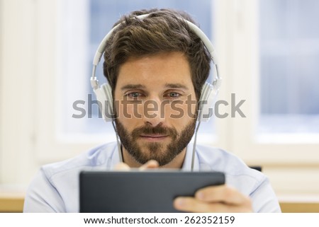 Man in office withe tablet pc and headphones