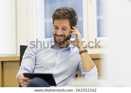 Handsome man holding digital tablet in office