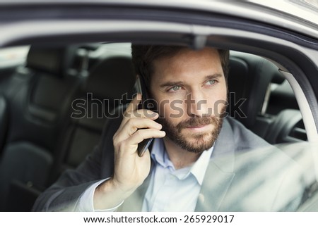 Casual business man on mobile phone in rear of the car