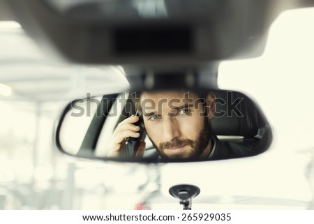 Man on mobile phone in the car. Reflection in the mirror