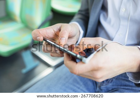 Man texting sms, using cell phone apps. video gaming on bus. Close-up hands
