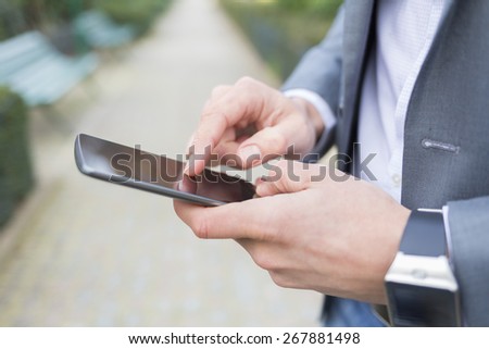 Man with Mobile phone connected to a smart watch; Close-up hands