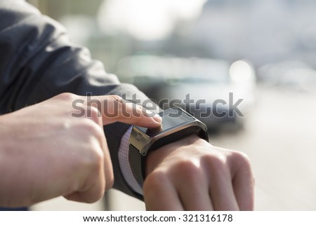 Outdoors man using his smart watch. Close-up hands