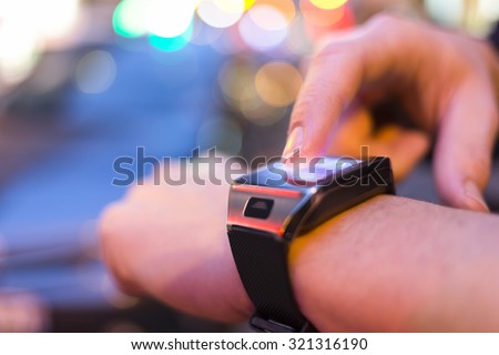 Man using his smart watch app in the street, night light bokeh Background. close up of male hands