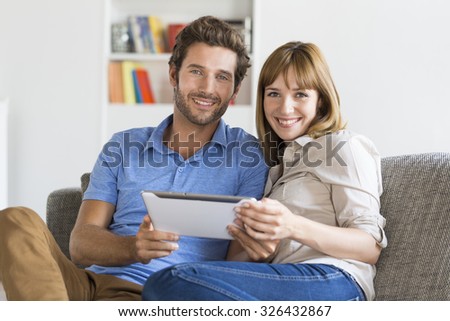 Thirty year old couple on app tablet pc in modern white home.