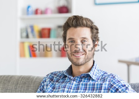 Cheerful bearbed hipster man in white modern house. Face camera