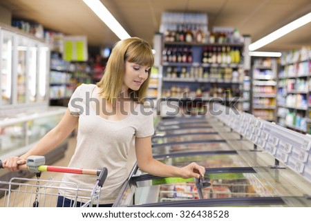 Cute woman chooses frozen products in supermarket