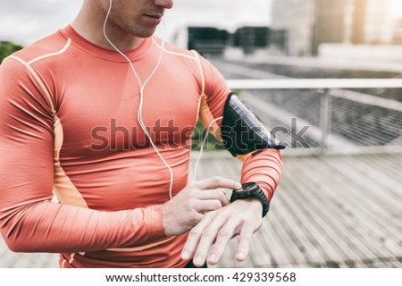 Urban runner man looking app on sportwatch. Male running jogging smart watch outside