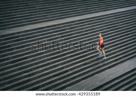Running athlete jogging outdoors listening to music on cell phone. Sport outside on wooden staircase