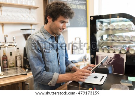 In a restaurant the waiter prepares the bill on computer POS tablet pc