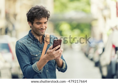 Cheerful male in the street texting on Mobile phone. Connection device