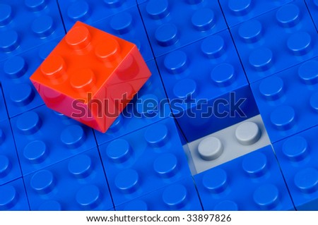 Red building block, ready to place into blue ones