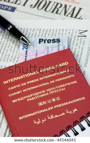 International press card, pen and memo-pad on newspaper