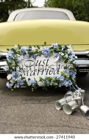 Bumper of limousine with just married sign and cans attached