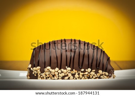 Chocolate coated bananas cake with nuts yellow background