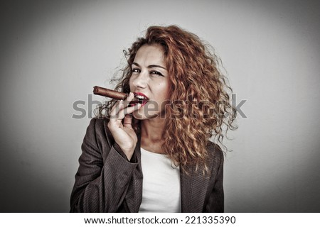 Closeup portrait of a young businesswoman smoking cigar and blowing smoke, on dark background