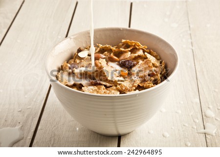 Appetizing view of milk pouring into a bowl of nutritious and delicious corn flake cereal