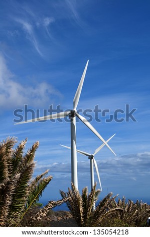 Wind turbine over blue sky on green meadow