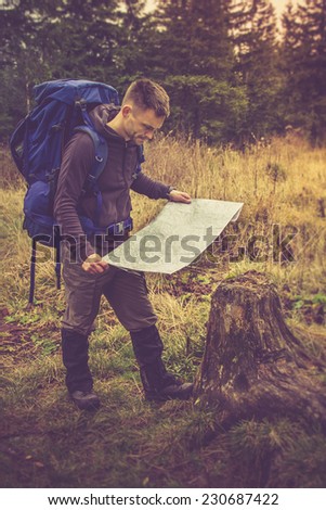 Backpacker with map to find directions in wilderness area.Filtered image:cross processed vintage effect.