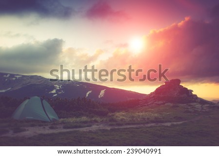 Landscape at tent camping in the mountains. Fantastic evening glowing by sunlight. Filtered image: Soft and vintage effect.